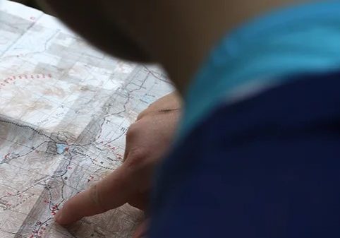 a finger pointing to a spot on a map