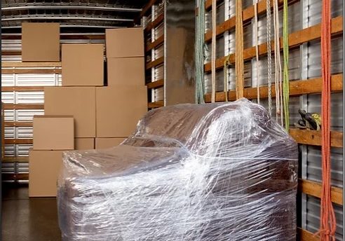 a sofa wrapped in plastic in a moving van