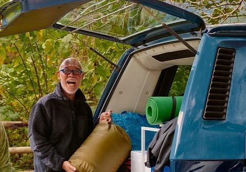 a man standing at the back of a hatchback holding a bag